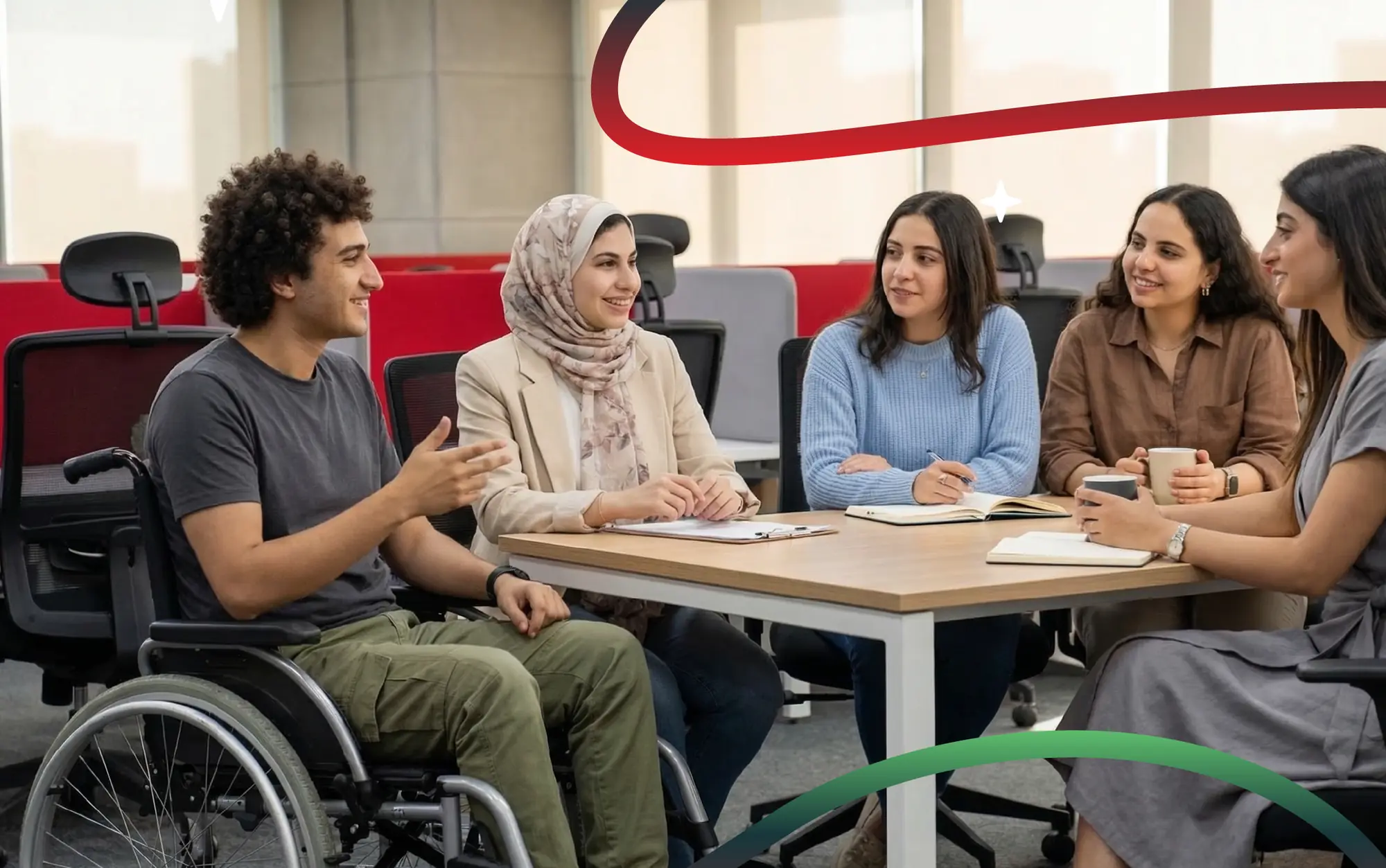 Diverse group of young graduates in conversation around an office table, framed by red brand ribbons