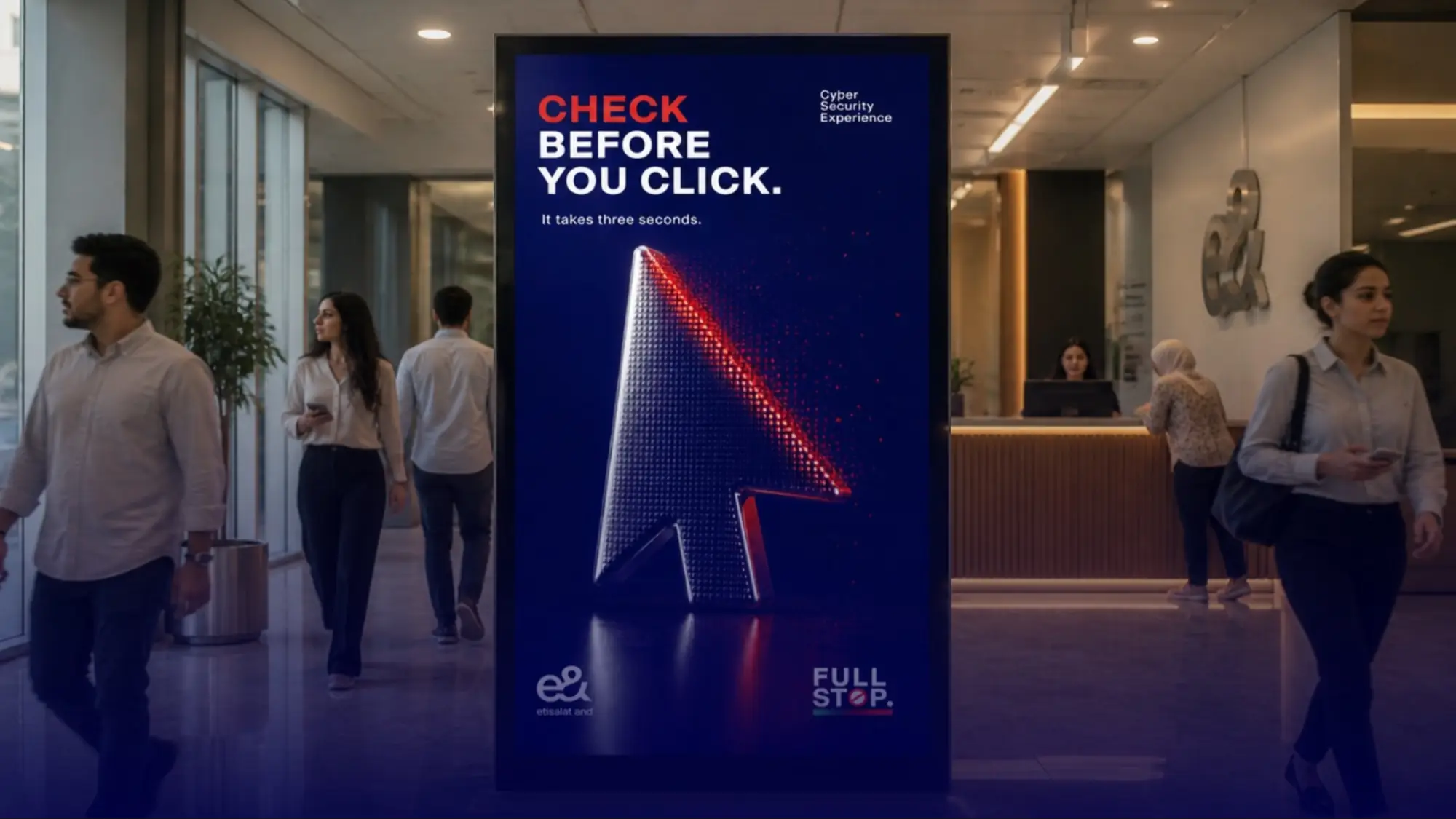 Office lobby poster warning staff to check before they click, as colleagues walk past