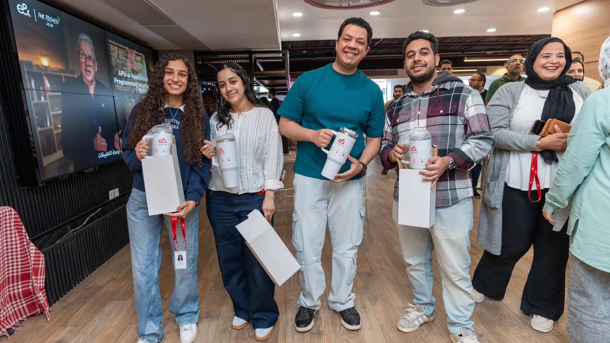 Men and women colleagues stand together smiling in a bright open office