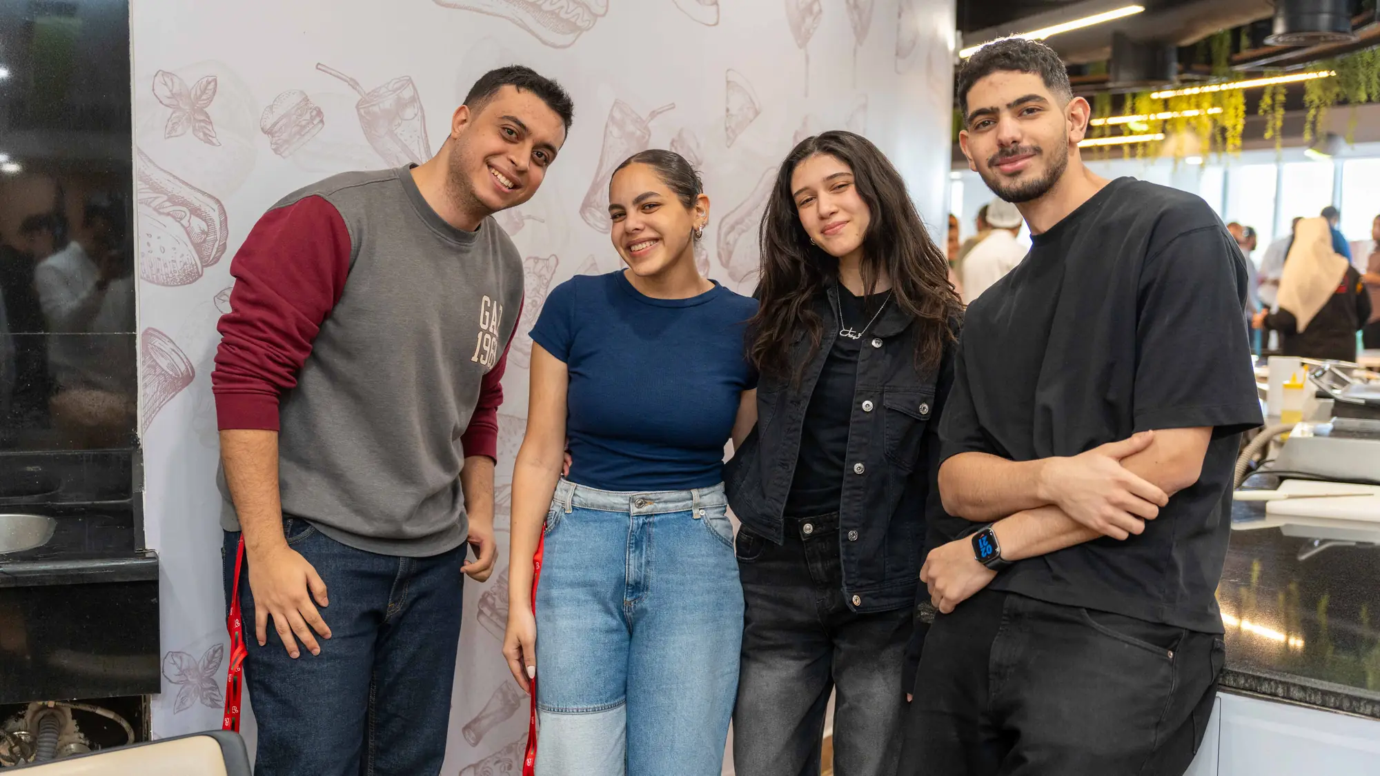 Four young colleagues, two women and two men, pose together in the office