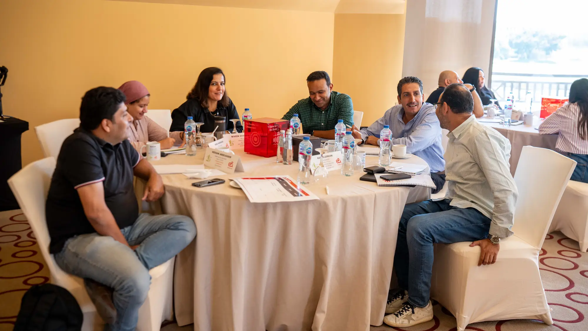 Small group of colleagues in lively discussion around a round workshop table