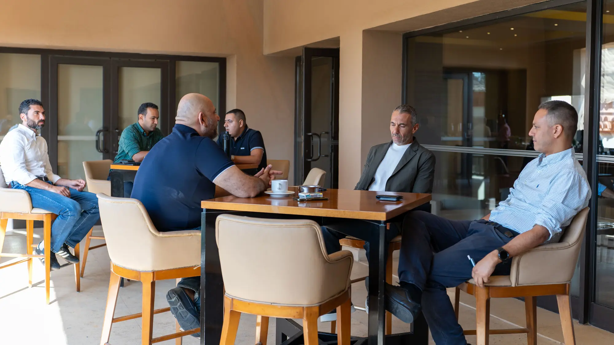 Five colleagues sit around a wooden table sharing views in a relaxed session