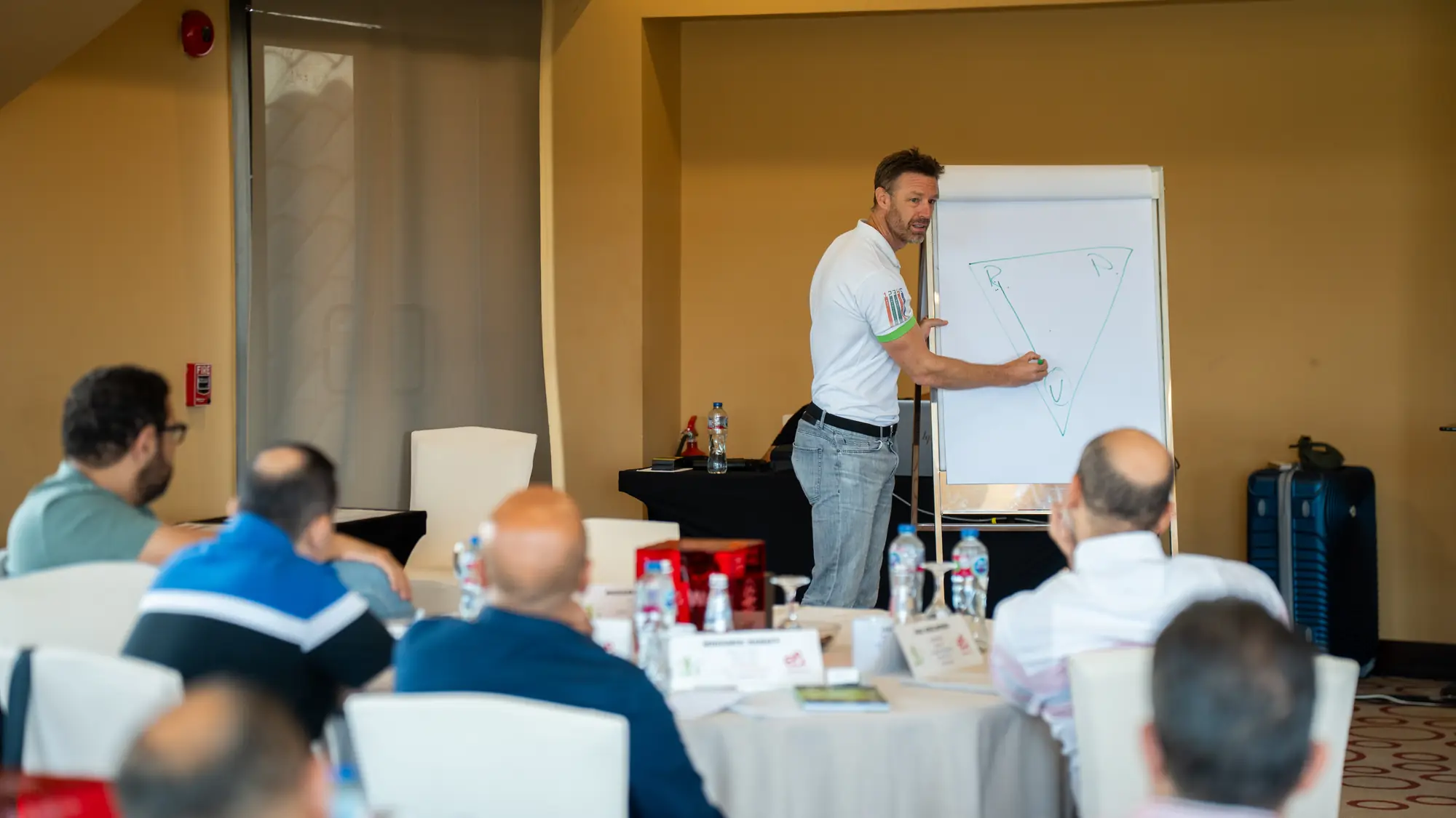 Facilitator sketches on a flipchart while seated participants follow the discussion