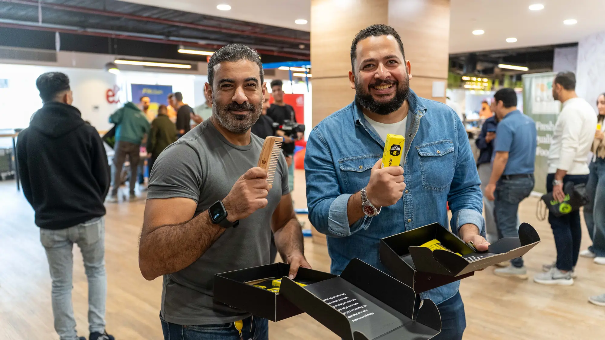Two smiling male colleagues show off the gift boxes they just received