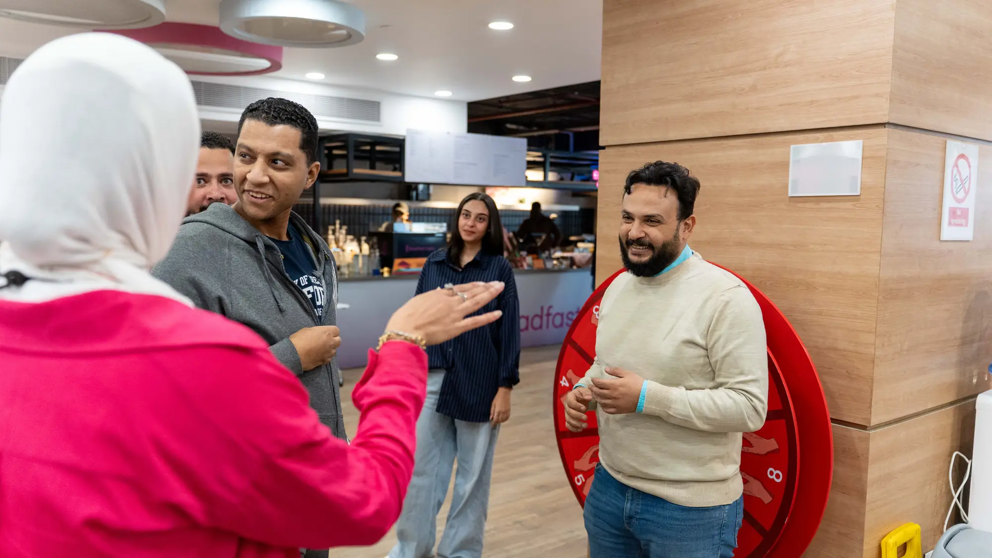 Colleagues chat and laugh together beside a prize wheel in the office