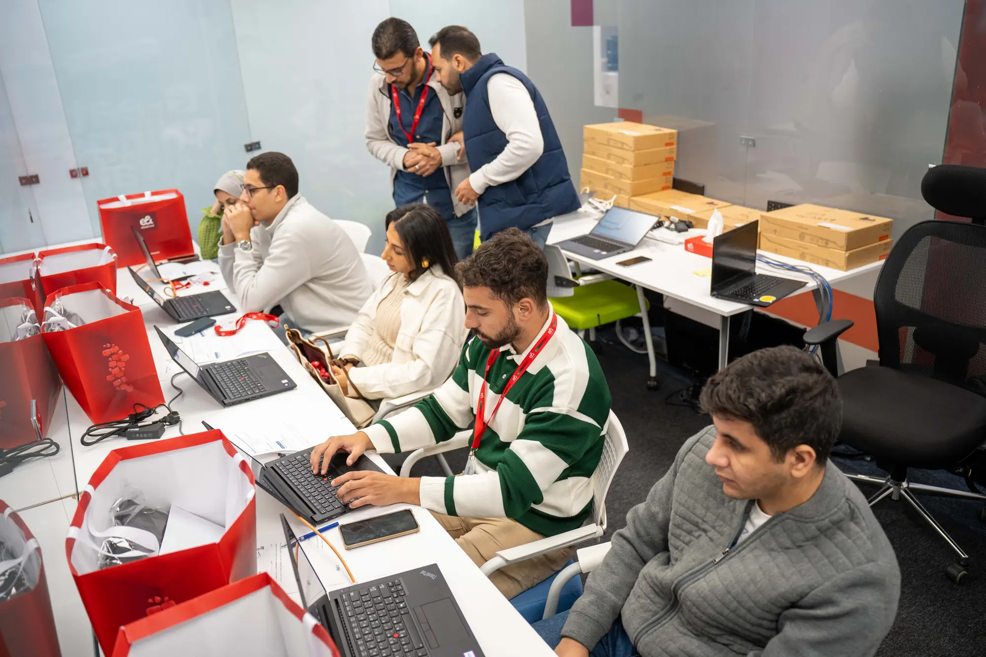 New hires setting up their laptops together at a long desk with staff helping
