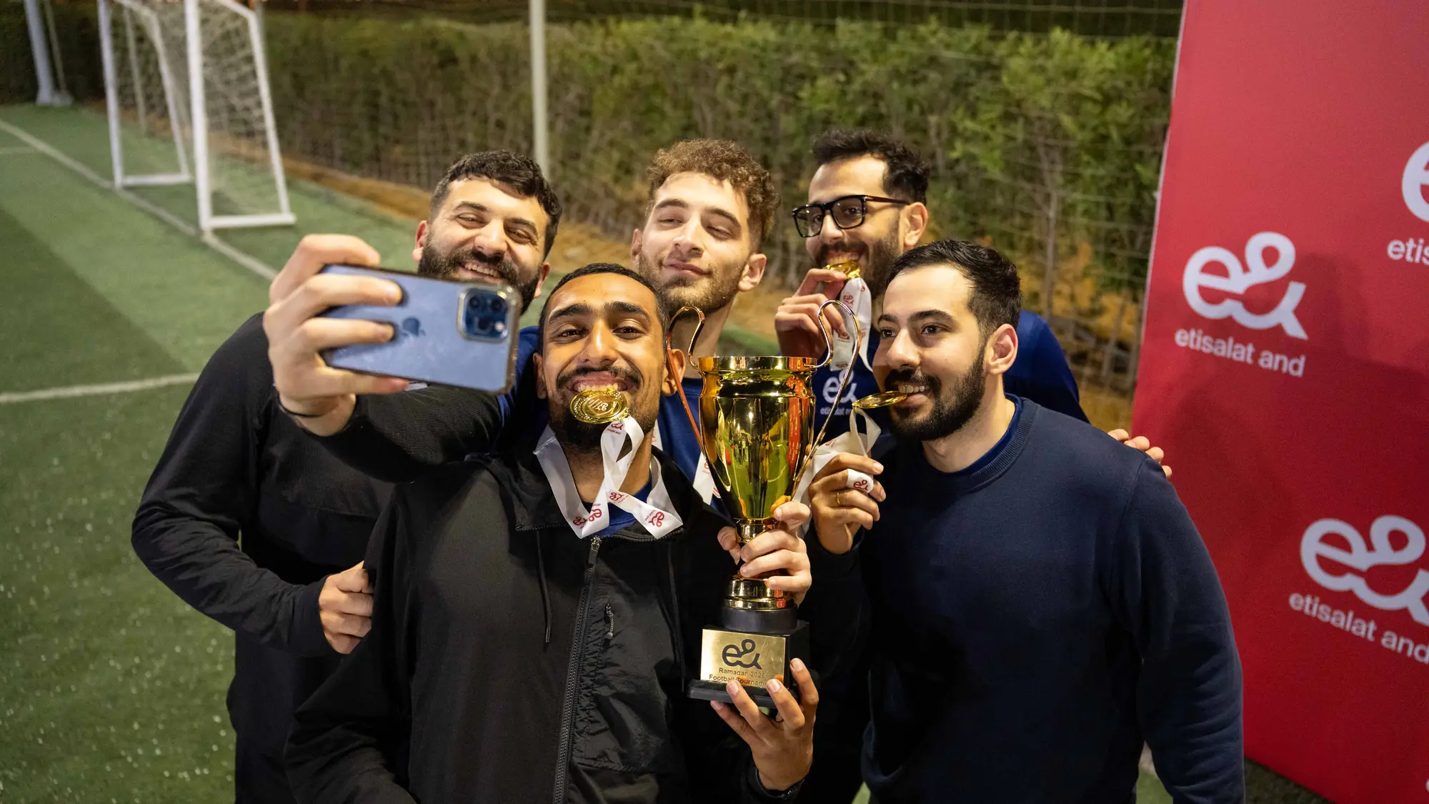 فريق كرة قدم فائز يلتقط صورة سيلفي احتفالية مع كأس ذهبية وميداليات
