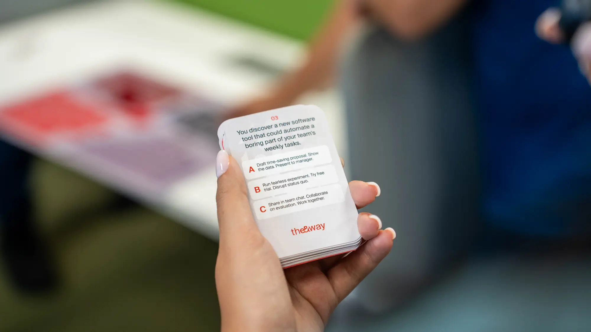 A hand holds a printed scenario card from the values game above the game board