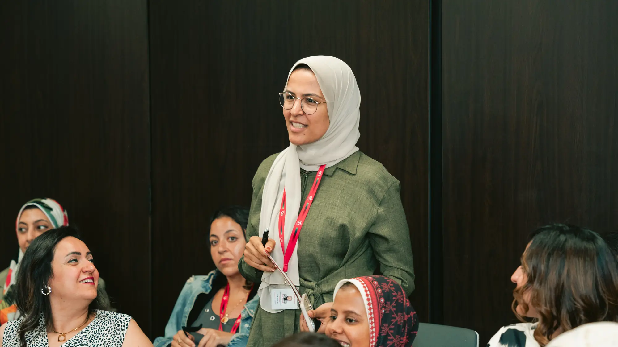 A woman stands to share her view while seated colleagues listen and smile